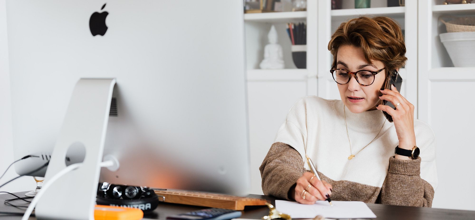 Image of woman writing with a pen and on a mobile telephone